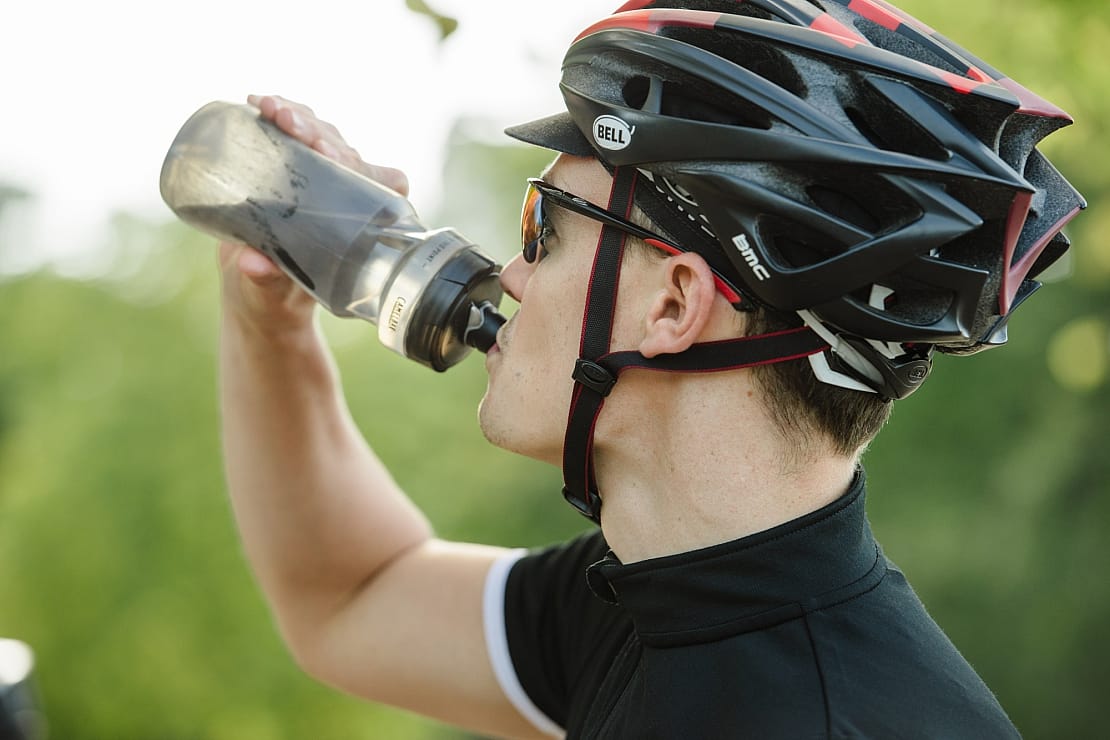 man with helmet drinking bottle