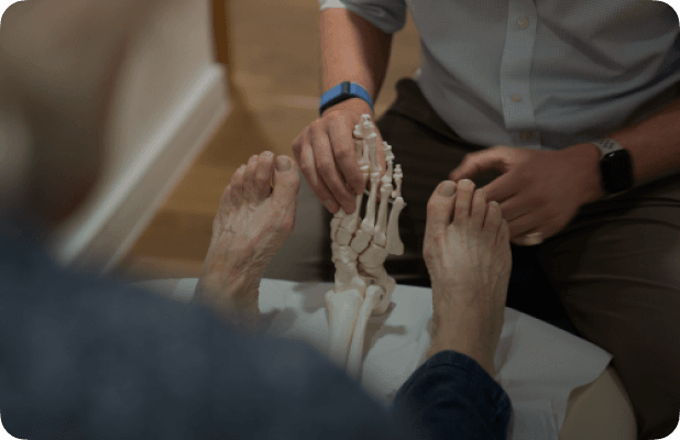 a clinician holding a model foot between a patient's foot