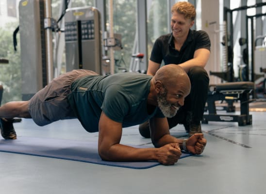 a man holding a plank in the gym with a physiotherapist