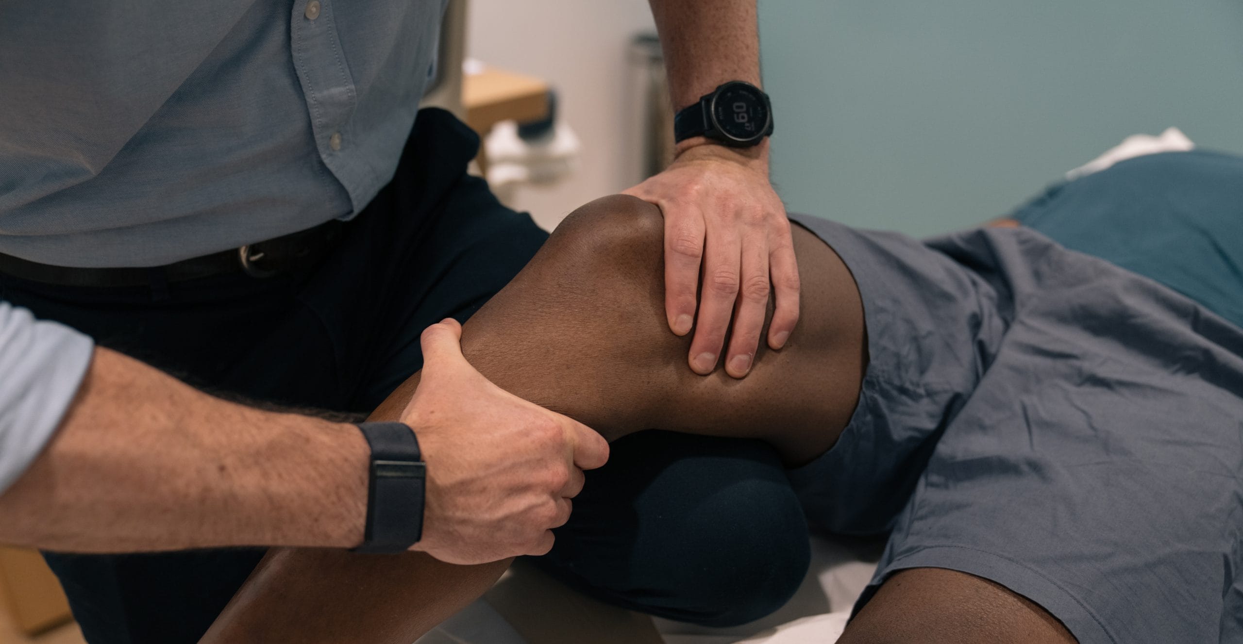 a clinician holding both hands on a patient's knee