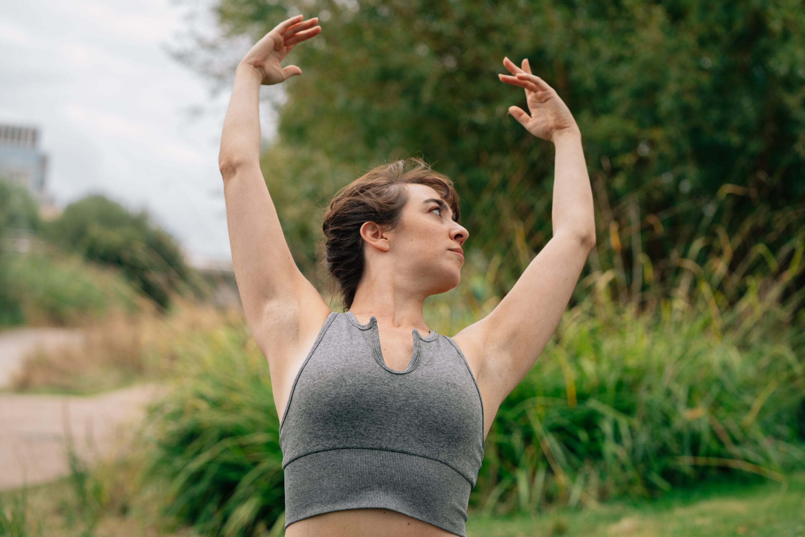 woman dancing outside with arms up close up