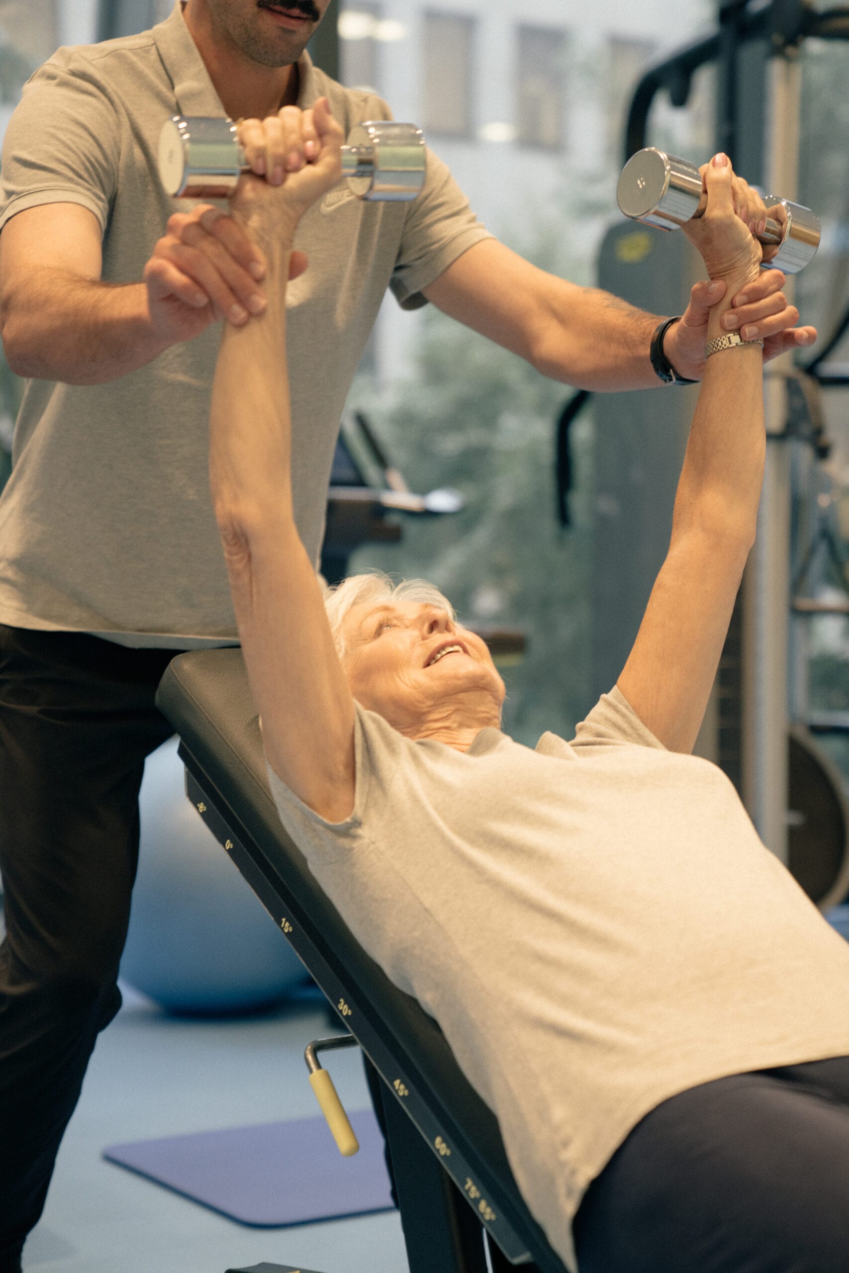 clinician holding older woman arms with weights