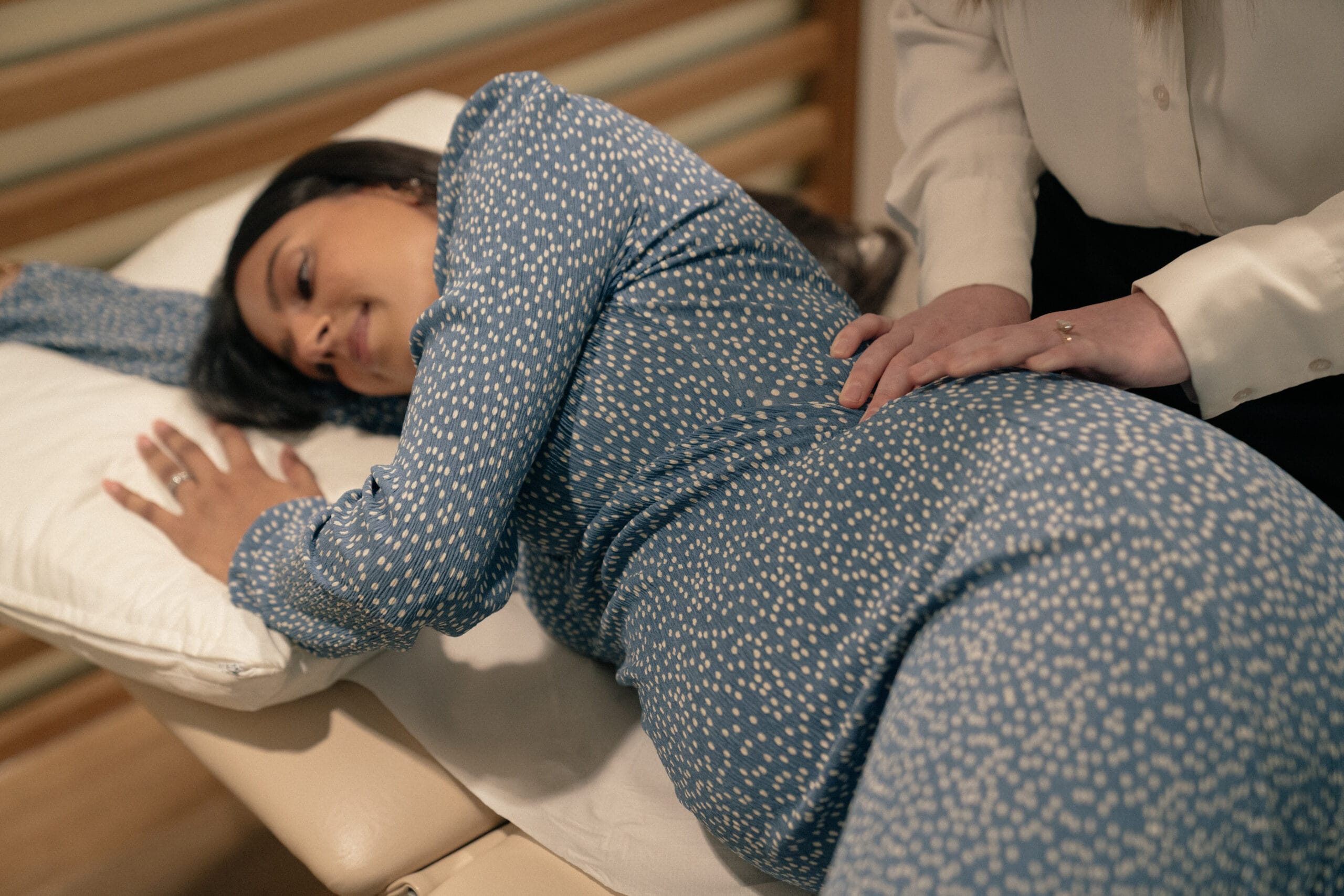 pregnant woman laying on her side on appointment bed