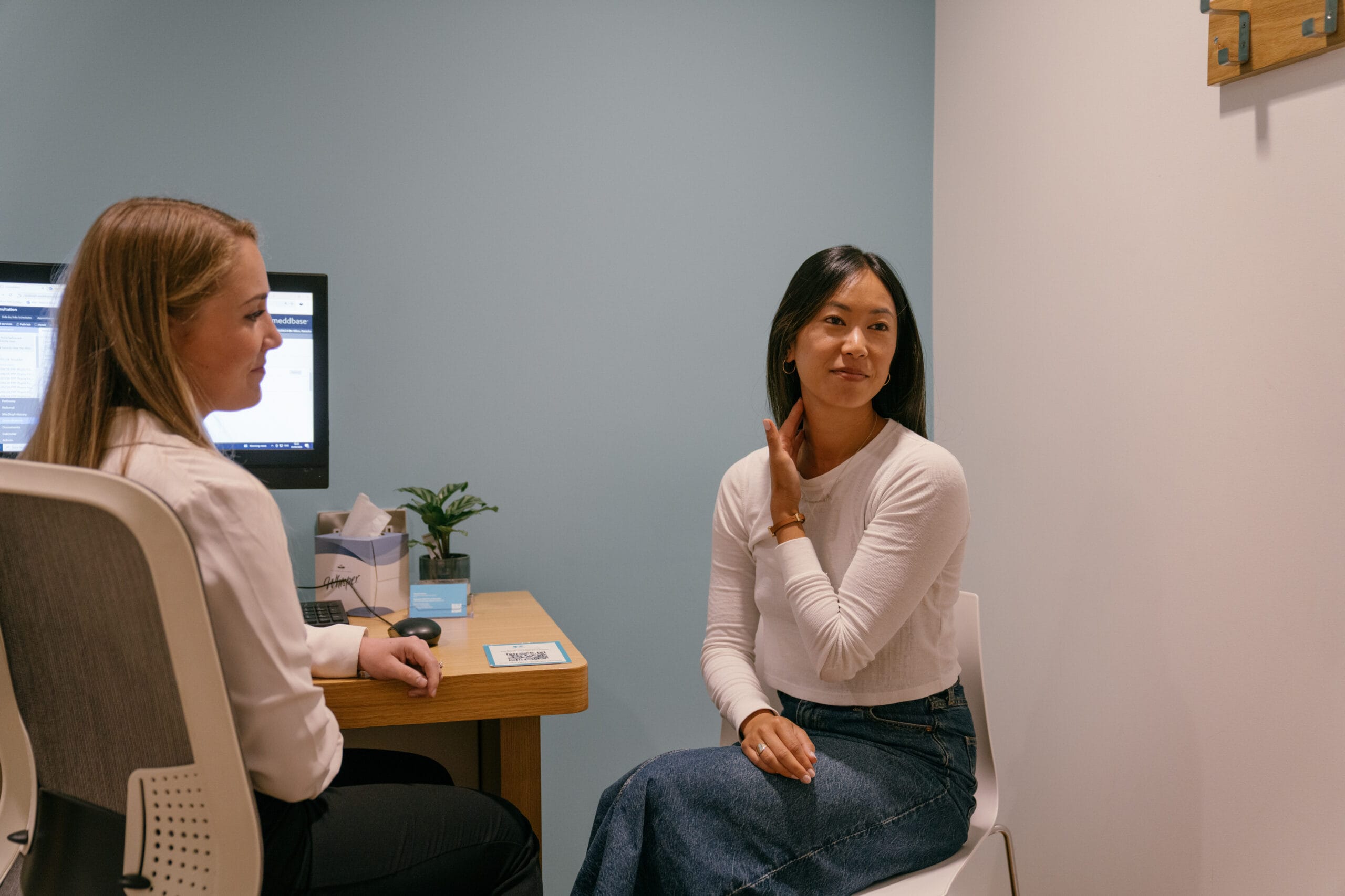 Patient pointing at her neck to doctor in appointment room