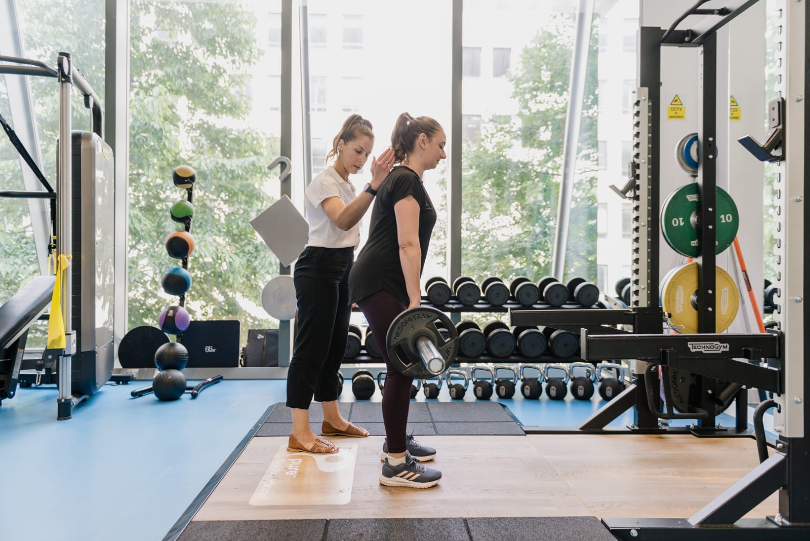 clinician holding patient's back when lifting weights