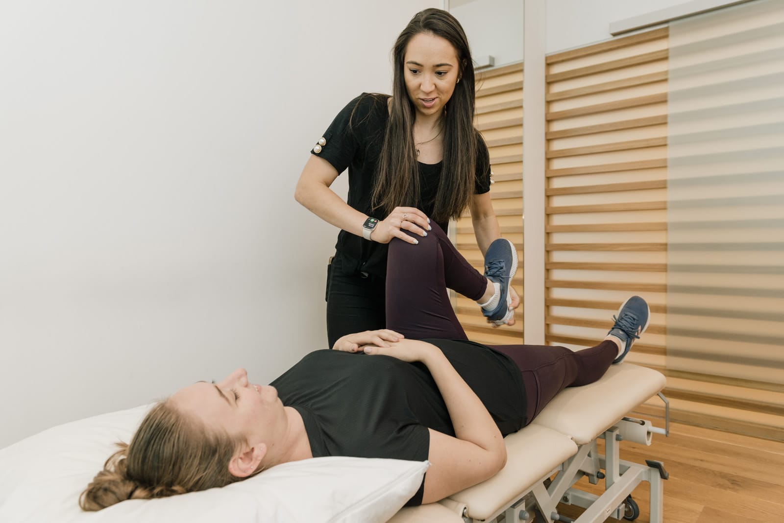 clinician holding patient's knee in assessment lying down