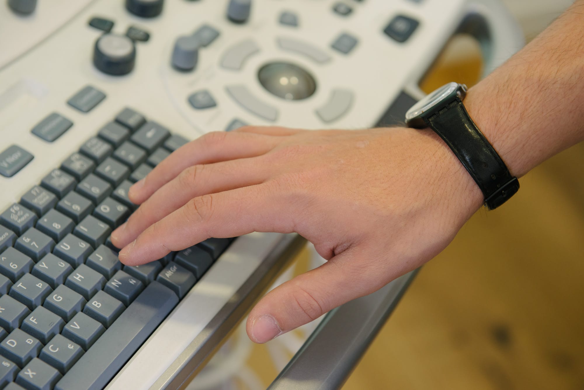 Hand with a watch typing on a keyboard