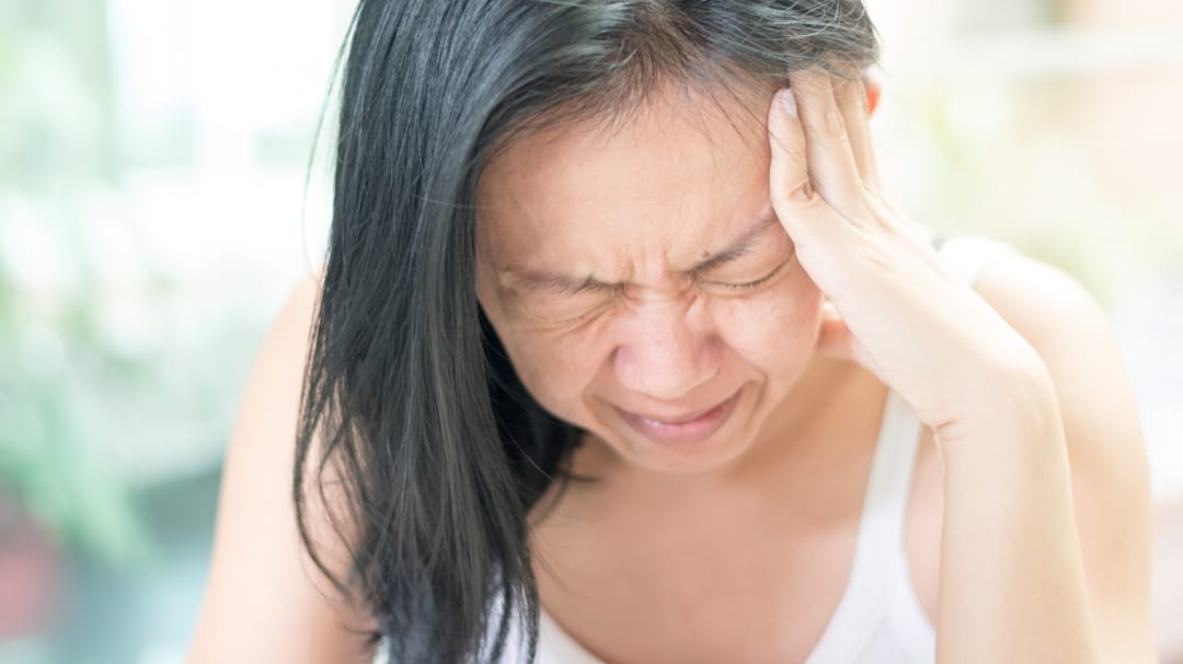 woman holding head in pain