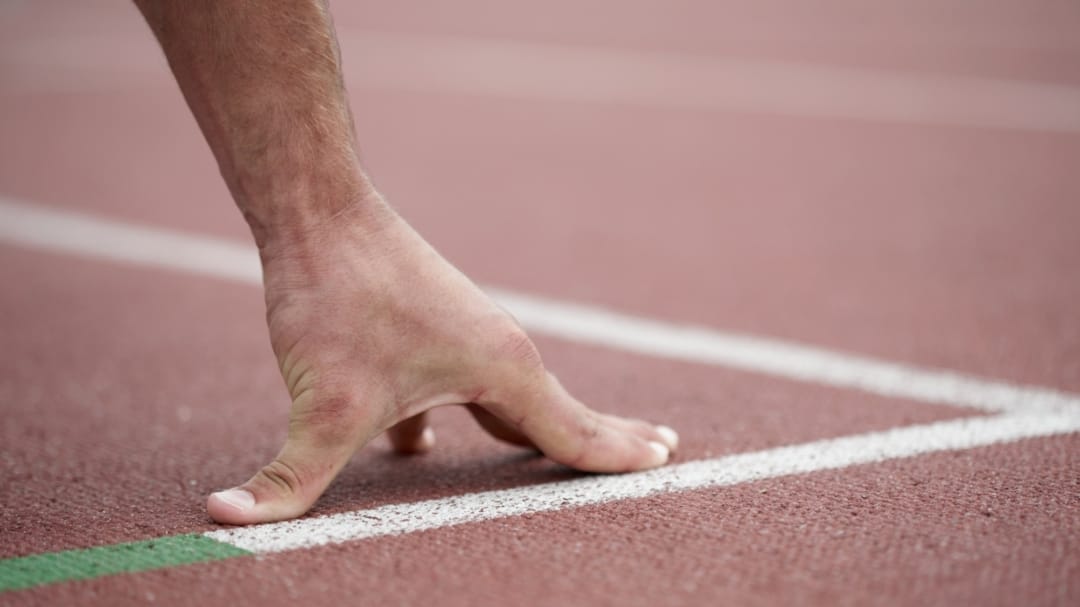 close up on runners hand on the track floor