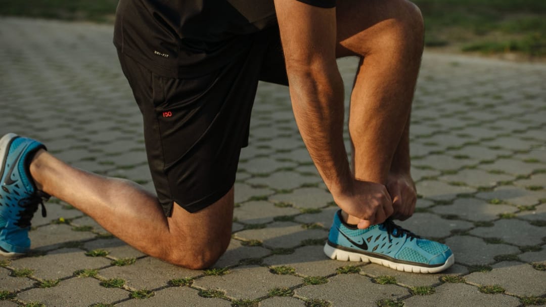 Runner kneeling to tie trainers shoe laces