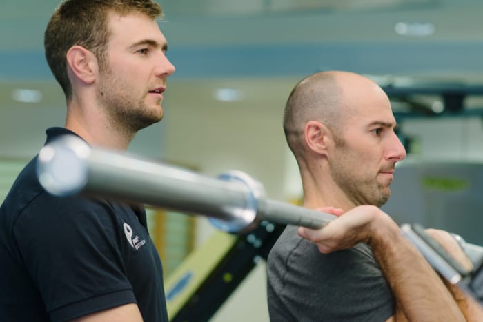 close up of patient and clinician lifting weights in recovery gym