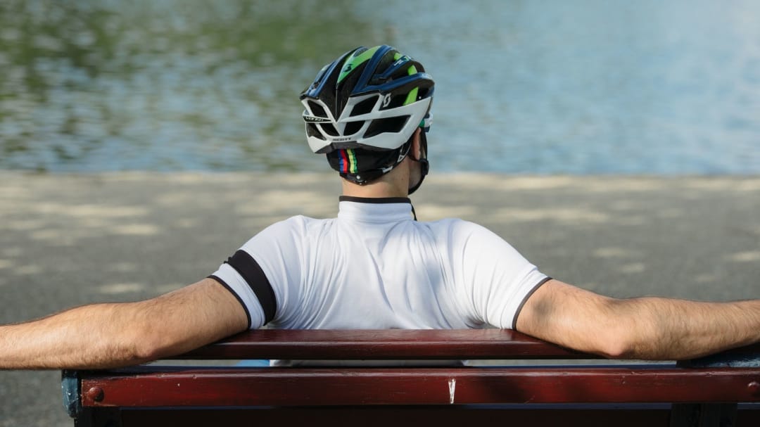 man with a helmet on resting on a bench