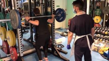 a patient lifting weights with clinician watching