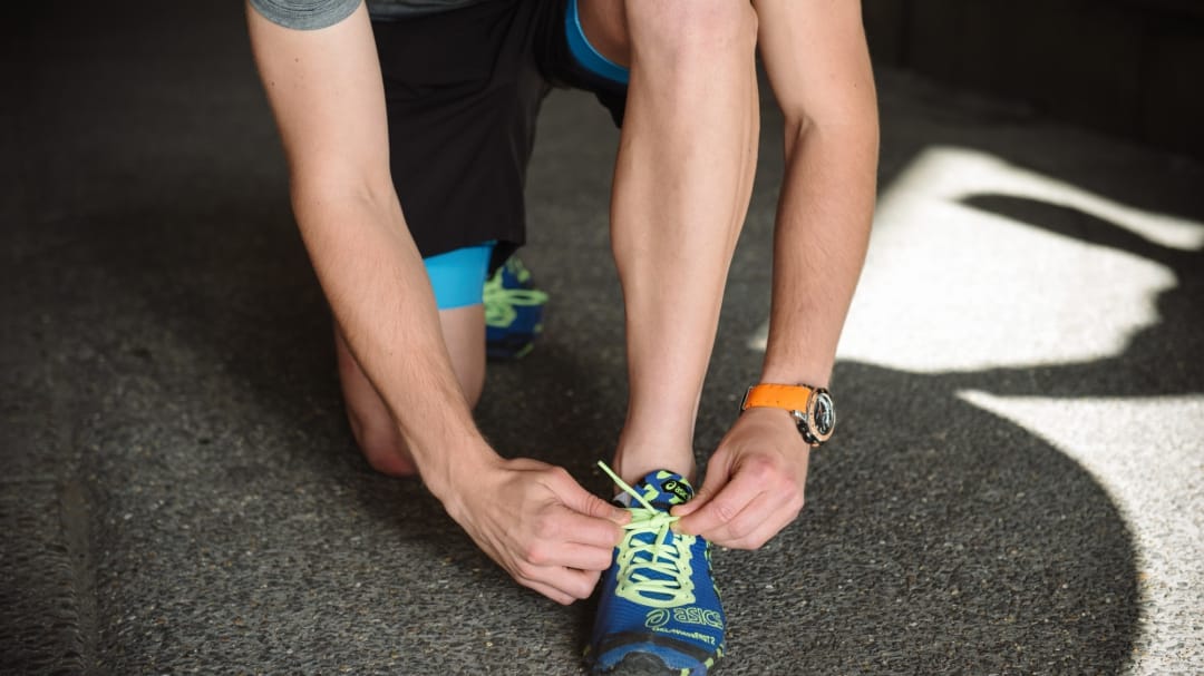 close up of a runner bending down to tie their shoe laces