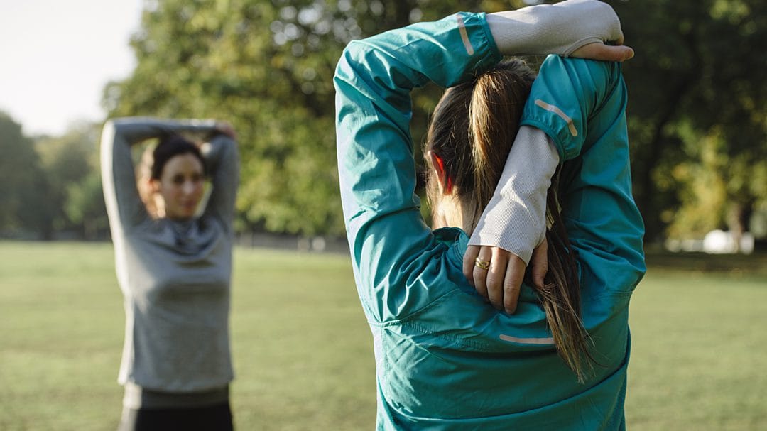 Two people stretching outside