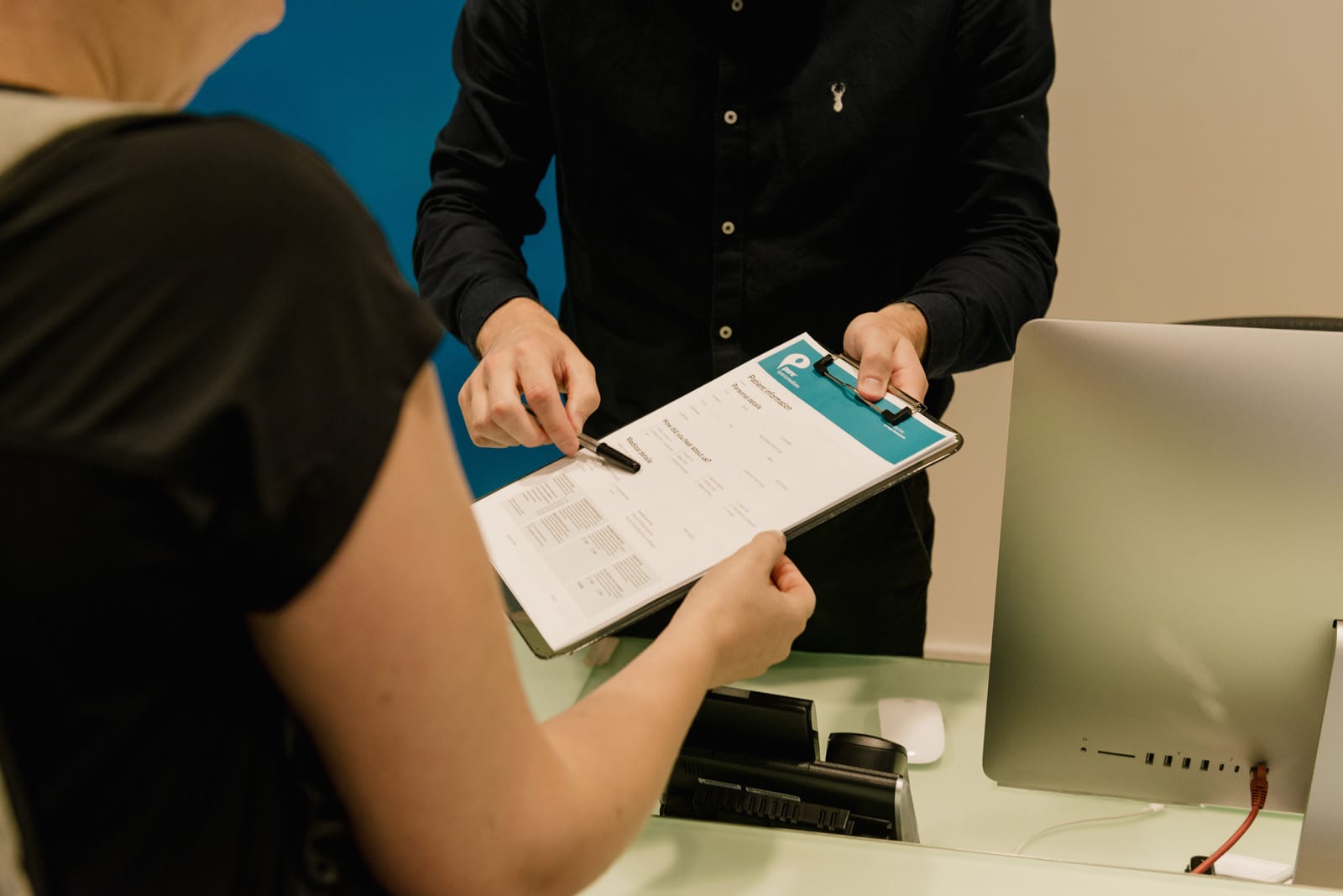 Receptionist giving patient Pure Sports Medicine form