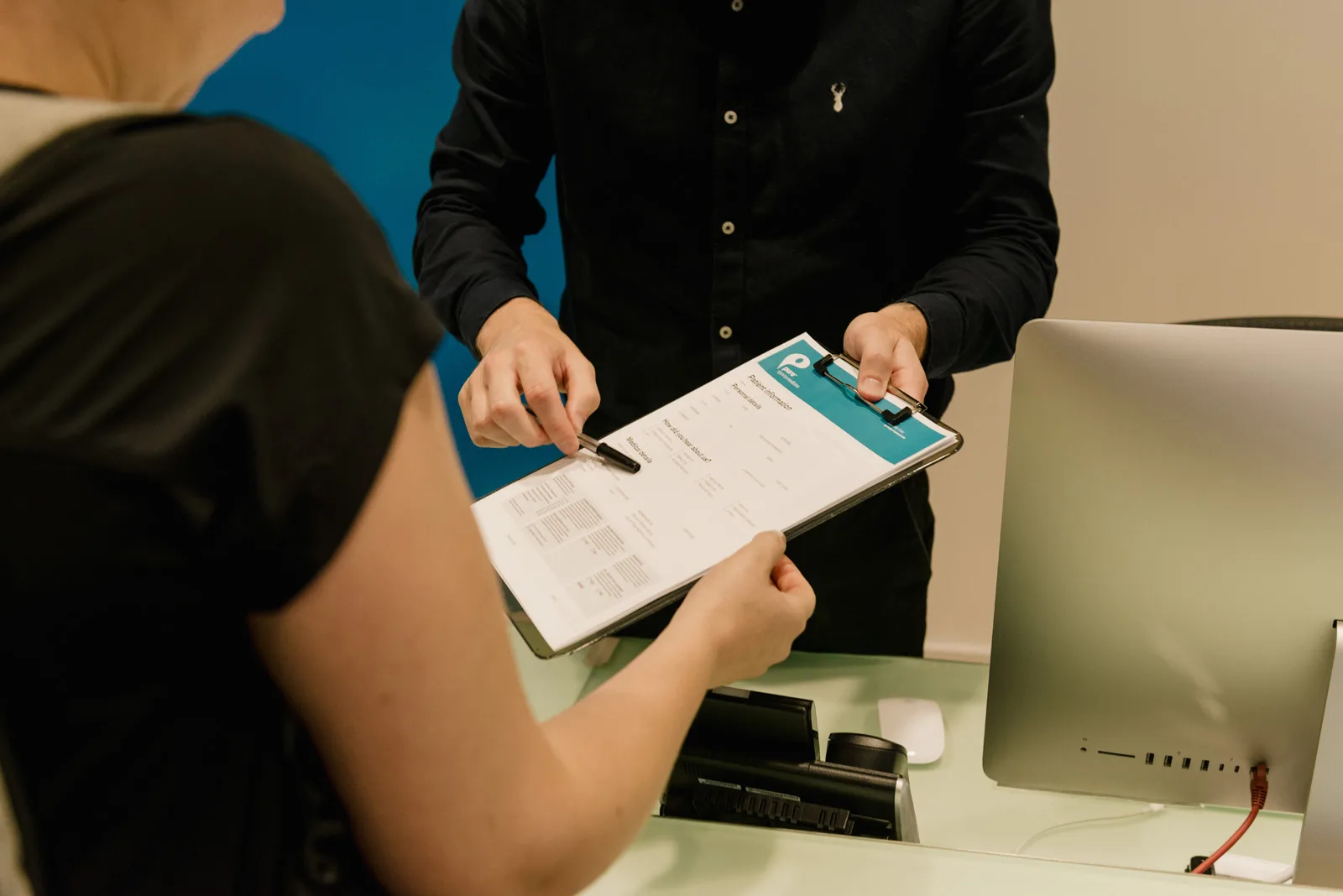 Receptionist giving patient Pure Sports Medicine form